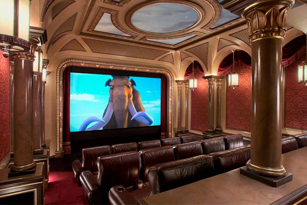 Traditional theater room with leather recliners in two rows, surrounded by ornate columns, red damask walls, and an overhead painted ceiling.