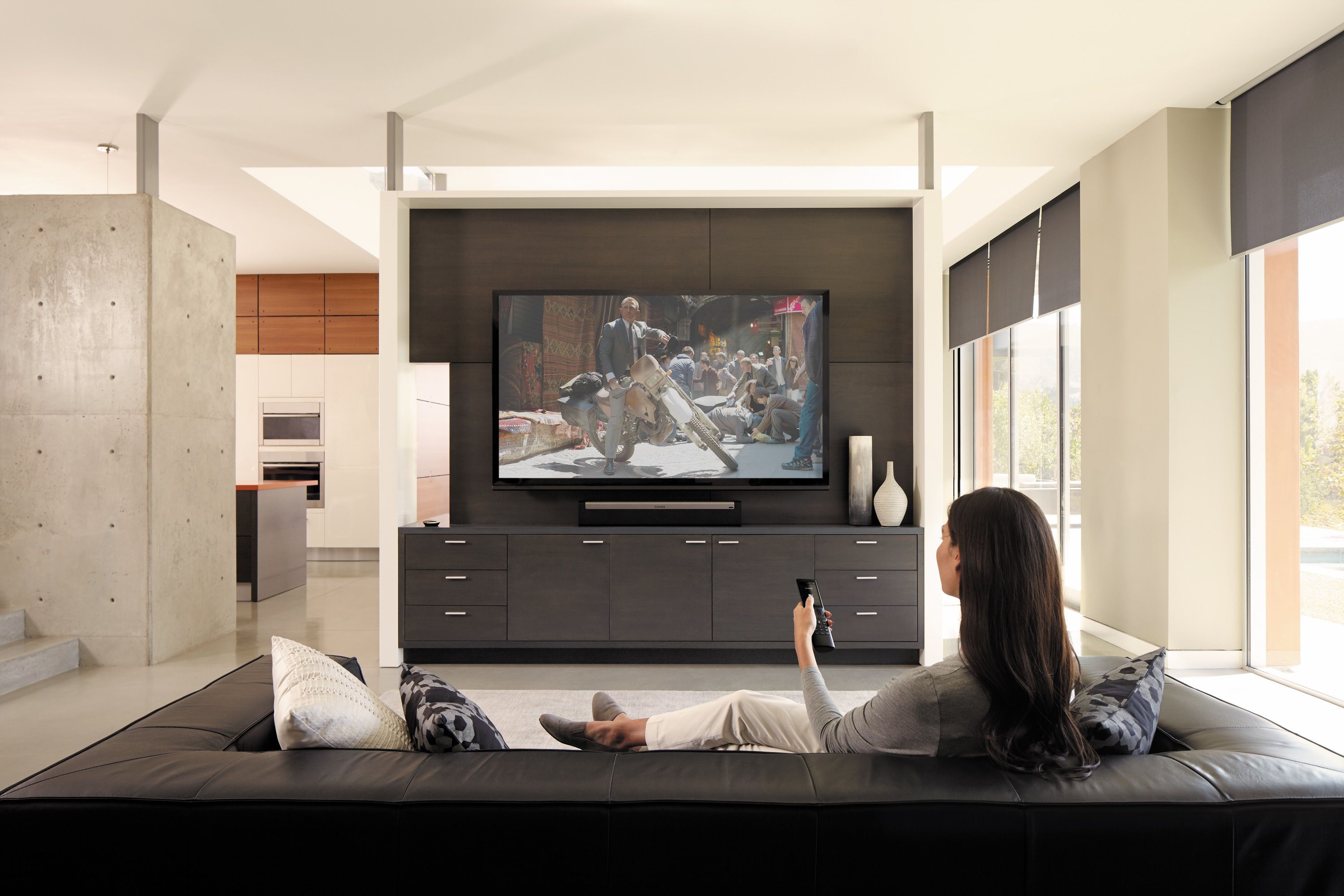 Contemporary home theater with sectional seating, wall-mounted screen, ambient lighting, and modern design elements including clean lines and neutral tones.